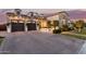 Evening shot of the residence with brick driveway, manicured hedges, and illuminated facade at 3684 E Boot Track Trl, Gilbert, AZ 85296
