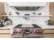 Close-up showcasing a high-end kitchen with a stainless steel range, stylish marble backsplash, and open shelving at 3684 E Boot Track Trl, Gilbert, AZ 85296