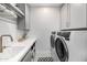 Well-appointed laundry room featuring modern washer and dryer, sink, marbled countertops, and ample cabinet space at 3684 E Boot Track Trl, Gilbert, AZ 85296