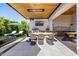 Covered outdoor kitchen with a TV, pizza oven, and stylish outdoor dining area at 3684 E Boot Track Trl, Gilbert, AZ 85296