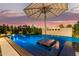 Captivating pool with sleek design, centered platform, elegant patio umbrellas, and integrated water feature at 3684 E Boot Track Trl, Gilbert, AZ 85296