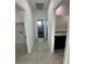 Bright hallway with neutral tile flooring, leading to bathroom and bedrooms at 38055 W Excussare Way, Maricopa, AZ 85138