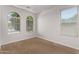 Bright, empty bedroom featuring neutral carpet, white walls, and large windows for optimal natural light at 41103 W Rio Bravo Dr, Maricopa, AZ 85138