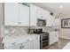 Well-equipped kitchen with white cabinets, quartz countertops, and a stainless steel gas range oven at 4898 N 206Th Ln, Buckeye, AZ 85396