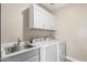 Bright laundry room featuring modern appliances, a sink, and ample white cabinet space for convenient storage at 4898 N 206Th Ln, Buckeye, AZ 85396