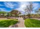 Backyard oasis with well-manicured artificial grass and a walkway leading to the pool and lounge area at 5712 E Blue Sky Dr, Scottsdale, AZ 85266