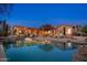 A stunning backyard oasis featuring a pool, outdoor seating, and beautifully lit landscaping at twilight at 5712 E Blue Sky Dr, Scottsdale, AZ 85266