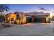 Charming desert home featuring a three-car garage, complemented by desert landscaping and warm exterior lighting at 5712 E Blue Sky Dr, Scottsdale, AZ 85266