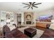 Cozy living room with a fireplace, built-in cabinets, and a ceiling fan adjacent to the kitchen at 5712 E Blue Sky Dr, Scottsdale, AZ 85266