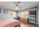 A bright bedroom with a ceiling fan, light wood floors, a desk, and a wire shelving unit at 6532 E Aster Dr, Scottsdale, AZ 85254