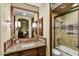Bathroom with granite counters, tiled shower, and wood cabinetry, plus a large, framed mirror at 6551 E Flat Iron Loop, Gold Canyon, AZ 85118