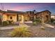 A beautifully landscaped front yard with a stone and stucco home featuring a covered porch and elegant entryway at 6551 E Flat Iron Loop, Gold Canyon, AZ 85118