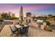 Outdoor kitchen with barbecue, seating and fireplace, set against a colorful sunset sky at 6551 E Flat Iron Loop, Gold Canyon, AZ 85118