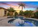 Stunning backyard pool featuring a waterfall and lush tropical landscaping at sunset at 6706 S Jacqueline Way, Gilbert, AZ 85298