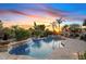 Tranquil backyard oasis featuring a sparkling pool, spa, and lush landscaping against a vibrant sunset backdrop at 6706 S Jacqueline Way, Gilbert, AZ 85298