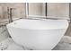 Freestanding white bathtub with marble surround, tile wall, and natural light from a window at 7439 E Beryl Ave, Scottsdale, AZ 85258