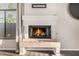 Close-up of fireplace with beige tile and burning logs at 7439 E Beryl Ave, Scottsdale, AZ 85258