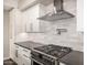Close-up of stainless steel stove and range hood with modern backsplash and gray countertops at 7439 E Beryl Ave, Scottsdale, AZ 85258