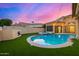 Beautiful backyard featuring a sparkling pool, spa, artificial turf, and charming string lights at sunset at 7439 E Beryl Ave, Scottsdale, AZ 85258
