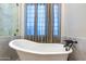 Bright bathroom featuring a standalone tub, marble walls, and a window with curtains at 8214 N 16Th St, Phoenix, AZ 85020