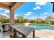 Charming covered patio with a dining table overlooking the pool and beautifully landscaped yard at 11324 E Diamond Cholla Dr, Scottsdale, AZ 85255