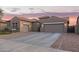 Charming single-story home featuring a three-car garage and low maintenance desert landscaping at sunset at 11957 W Daley Ln, Sun City, AZ 85373