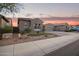 Charming single-story home featuring a three-car garage and low maintenance desert landscaping at sunset at 11957 W Daley Ln, Sun City, AZ 85373