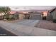 Charming single-story home featuring a three-car garage and low maintenance desert landscaping at sunset at 11957 W Daley Ln, Sun City, AZ 85373