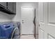 Laundry room with front-load washer, upper cabinets, and door to utility access at 11957 W Daley Ln, Sun City, AZ 85373