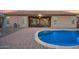 Backyard with sparkling pool, brick patio, and covered seating area with outdoor TVs at 11957 W Daley Ln, Sun City, AZ 85373