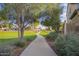 Community walking path with mature trees, lush grass, and well-maintained landscaping at 11957 W Daley Ln, Sun City, AZ 85373