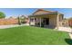 A well-maintained backyard featuring green lawn, a covered patio, and hardscape at 12425 W Willow Ave Ave, El Mirage, AZ 85335