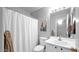 Bright bathroom featuring a white vanity, toilet, and shower with white curtain and a decorative southwest picture at 14952 W Maui Ln, Surprise, AZ 85379