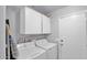 Functional laundry room with white washer, dryer, and cabinetry for ample storage space at 14952 W Maui Ln, Surprise, AZ 85379