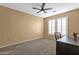Bedroom featuring carpet flooring, tan walls, and bright light filtering window shutters at 16401 S 29Th Ave, Phoenix, AZ 85045