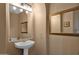 Charming powder room featuring a pedestal sink, decorative mirror, and neutral color scheme at 16401 S 29Th Ave, Phoenix, AZ 85045
