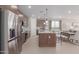 Open-concept kitchen with stainless steel appliances, island seating, and seamless flow into the dining and living areas at 18161 W Cielo Grande Ave, Surprise, AZ 85387