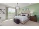 Bright and airy main bedroom with large windows, stylish drum pendant lighting, and sophisticated green accent wall at 18161 W Cielo Grande Ave, Surprise, AZ 85387