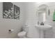 Charming powder room featuring shiplap accent wall, pedestal sink, and tasteful floral artwork for a touch of elegance at 18161 W Cielo Grande Ave, Surprise, AZ 85387