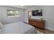 Cozy bedroom with warm wood dresser, mounted TV, and two sunny windows at 1839 E Palo Verde Dr, Phoenix, AZ 85016