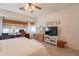 Main bedroom with ceiling fan, large window, wood floors, and a TV with decorative bureau at 19347 E Thornton Rd, Queen Creek, AZ 85142