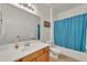 A traditional bathroom featuring wood cabinets, a large mirror, and a shower with a blue curtain at 209 N 237Th Ave, Buckeye, AZ 85396