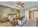 The spacious carpeted main bedroom features a ceiling fan, a large bed, and a white bench in front of bathroom entrance at 209 N 237Th Ave, Buckeye, AZ 85396