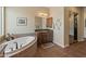 Bathroom with a soaking tub, dark wood cabinets and tile floors, plus a framed artwork on the wall at 31705 N 128Th Dr, Peoria, AZ 85383