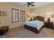 Spacious bedroom featuring two windows with plush carpeting, side tables and a ceiling fan at 31705 N 128Th Dr, Peoria, AZ 85383