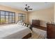 Bright bedroom featuring a large window overlooking the pool, a ceiling fan, and classic wood furniture at 31705 N 128Th Dr, Peoria, AZ 85383