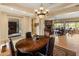 Open concept dining room with a wood table, chandelier and view into the living room with a fireplace at 31705 N 128Th Dr, Peoria, AZ 85383