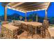 Gourmet outdoor kitchen with grill and dining under a wooden pergola, offering desert mountain views at 31705 N 128Th Dr, Peoria, AZ 85383