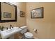 Stylish powder room with a pedestal sink, framed mirror, and tasteful decor at 31705 N 128Th Dr, Peoria, AZ 85383