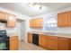 Functional kitchen with light wood cabinets, essential appliances, and a view to the backyard window at 3365 N Sunaire --, Mesa, AZ 85215